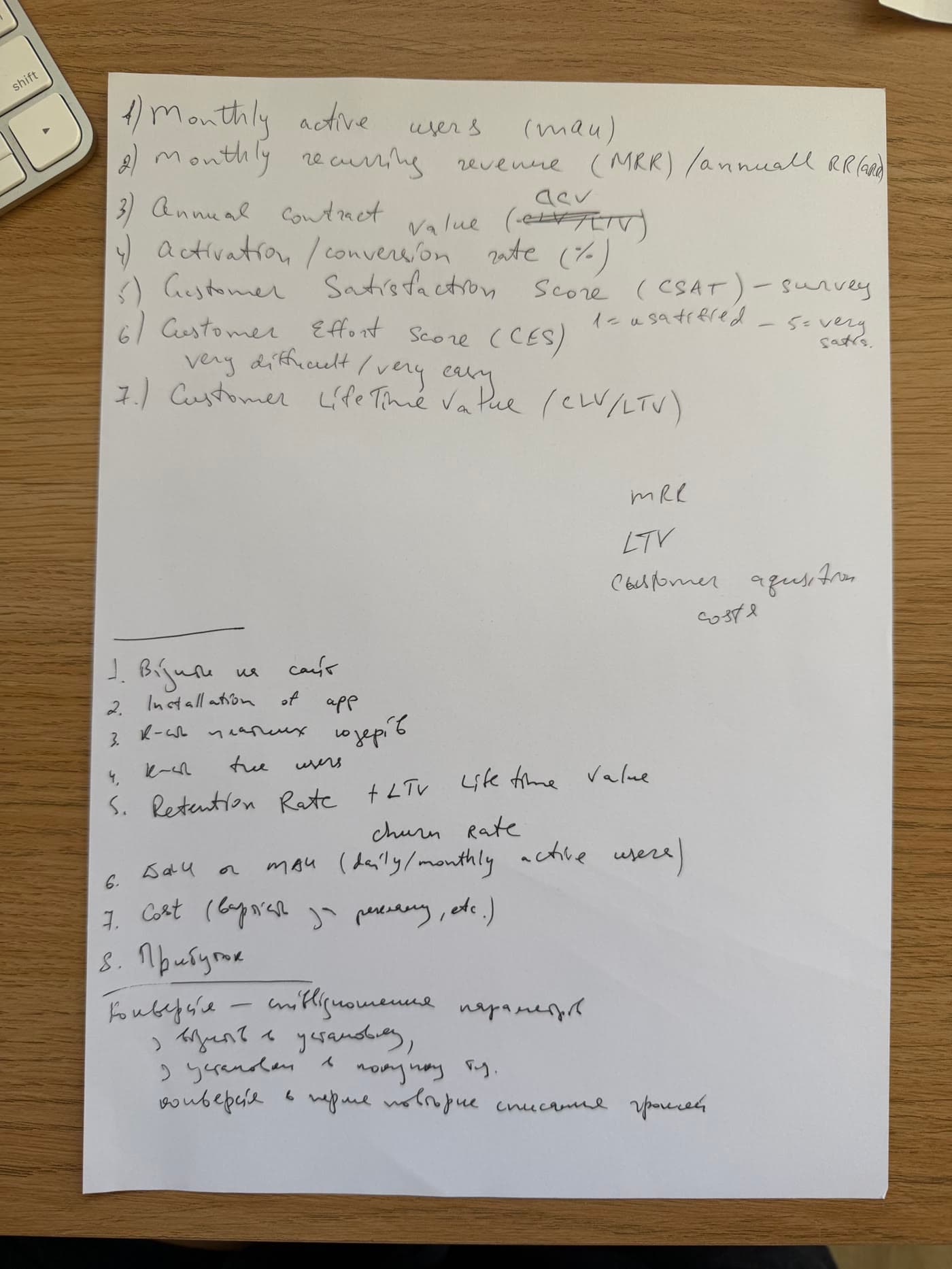 A sheet of paper with a hand-written list of candidate metrics: active users, recurring revenue, activation, satisfaction, lifetime value, retention, churn