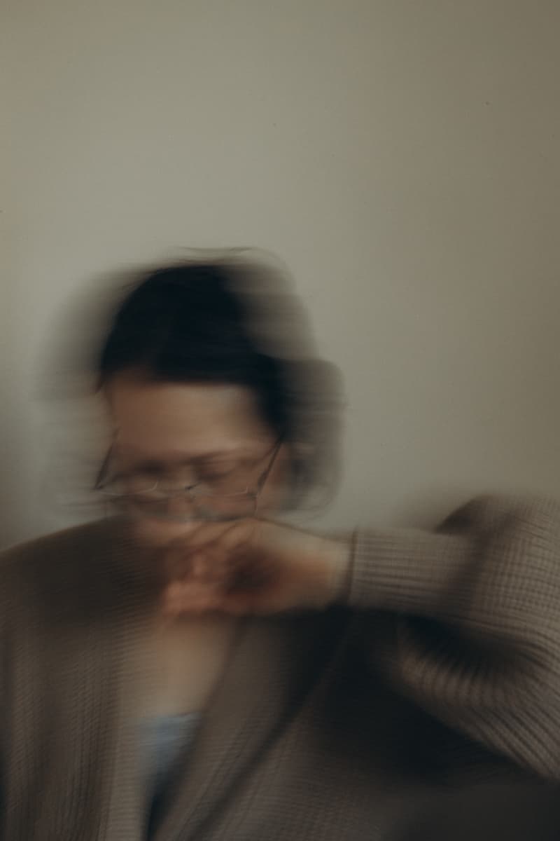 Self-portrait with a hand raised to the face, blurred in motion